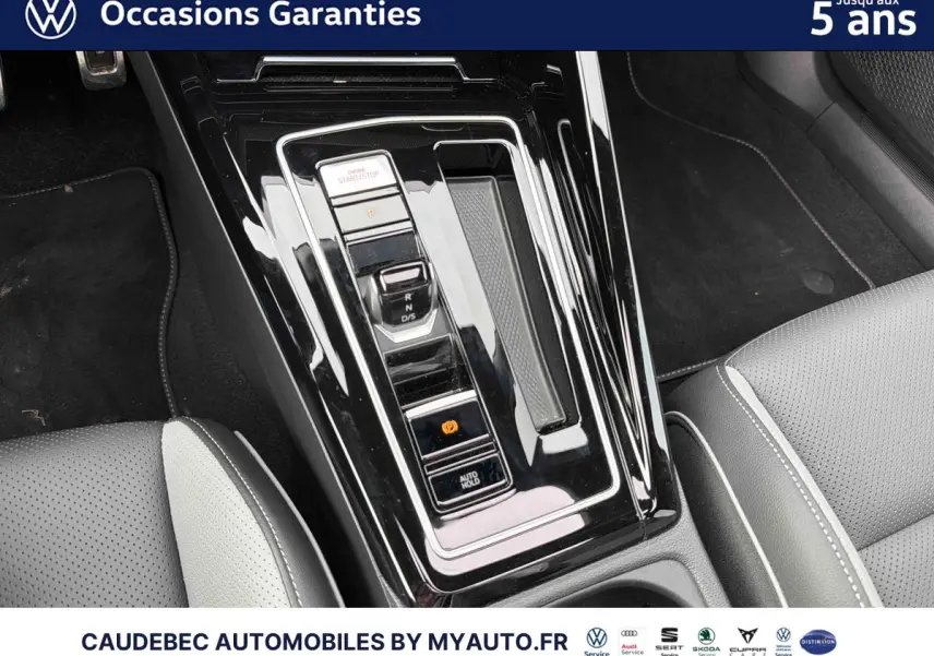 Gros plan sur la console centrale noire brillante avec levier de vitesses et sièges cuir gris clair de la Volkswagen Golf 1.5 eHybrid.