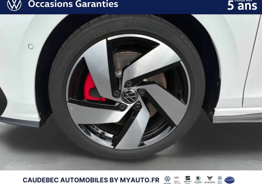Gros plan sur la roue avant gauche blanche d'une Volkswagen Golf 1.5 eHybrid 2025 avec jante alliage bicolore et étrier de frein rouge.