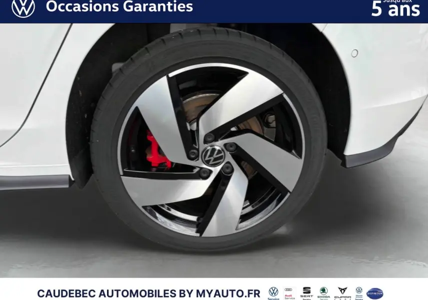 Gros plan sur la roue arrière droite d'une Volkswagen Golf 1.5 eHybrid blanche avec jante alliage noir et argent et étrier de frein rouge visible.