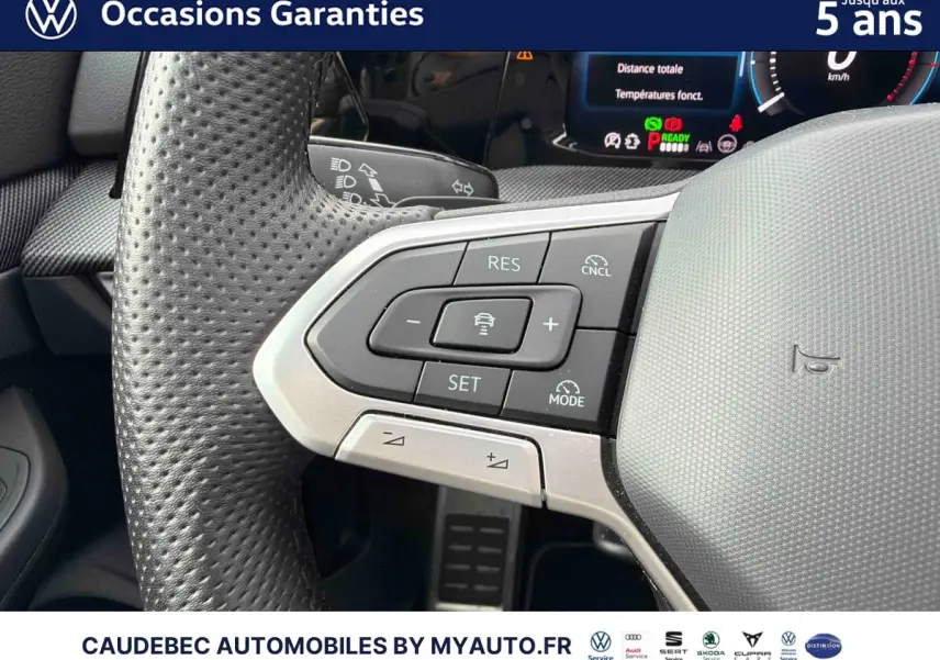 Gros plan sur le volant multifonction en cuir perforé de la Volkswagen Golf 1.5 eHybrid 2025 avec commandes de régulateur adaptatif.