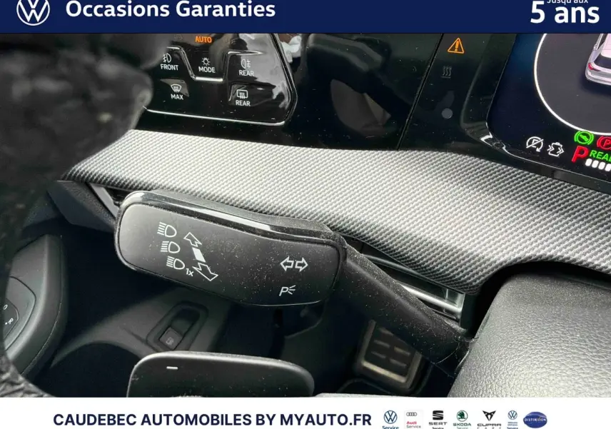 Détail intérieur du levier de clignotant et commandes au volant d’une Volkswagen Golf 1.5 eHybrid blanche, vue rapprochée.