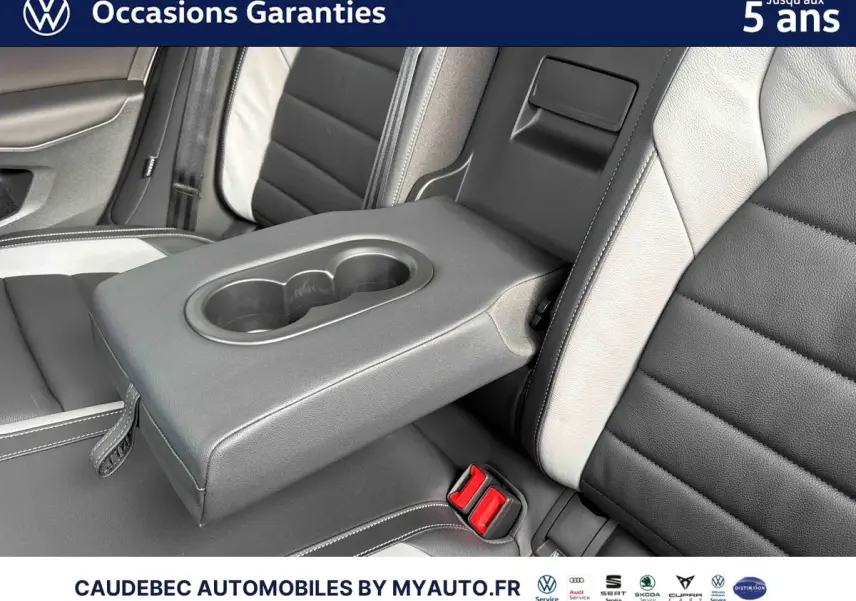 Détail de l'accoudoir central arrière avec porte-gobelets sur sellerie cuir bicolore noir et blanc de Volkswagen Golf 1.5 eHybrid 2025.