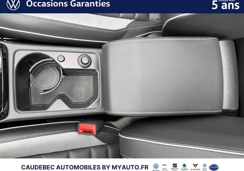 Gros plan sur la console centrale noire avec accoudoir cuir et porte-gobelet de la Volkswagen Golf 1.5 eHybrid blanche.