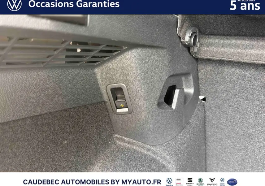 Détail intérieur du coffre côté droit d'une Volkswagen Golf 1.5 eHybrid blanche, montrant une commande de rabattement des sièges.