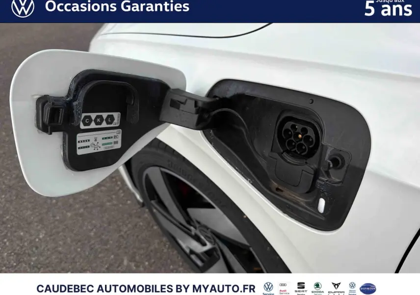 Prise de recharge ouverte côté arrière droit d’une Volkswagen Golf 1.5 eHybrid blanche avec jante alliage noir brillant.