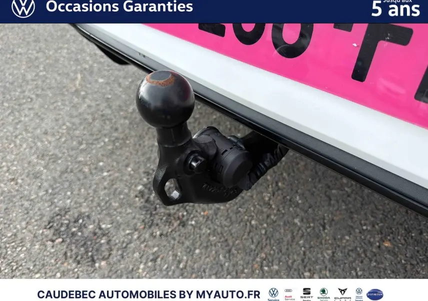 Gros plan sur l'attelage escamotable noir sous le pare-chocs arrière blanc d'une Volkswagen Golf 2025.