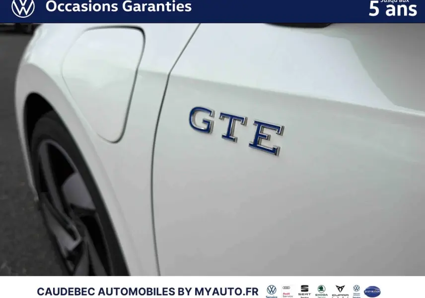 Gros plan sur l'aile arrière gauche blanche d'une Volkswagen Golf 1.5 eHybrid 272 DSG6 avec logo GTE bleu.