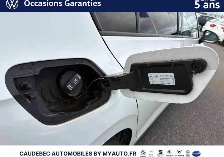 Détail de la trappe à carburant ouverte côté gauche sur une Volkswagen Golf 1.5 eHybrid blanche, vue rapprochée.