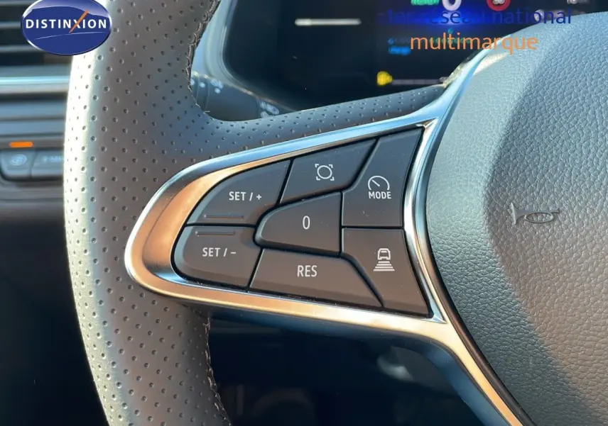 Gros plan sur les commandes au volant perforé du Renault Captur blanc nacré toit gris, version hybride 2025.