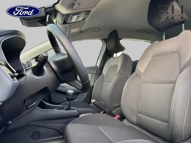 Vue intérieure côté conducteur de la Renault Clio blanche 2020 avec sièges tissu noir et volant réglable.