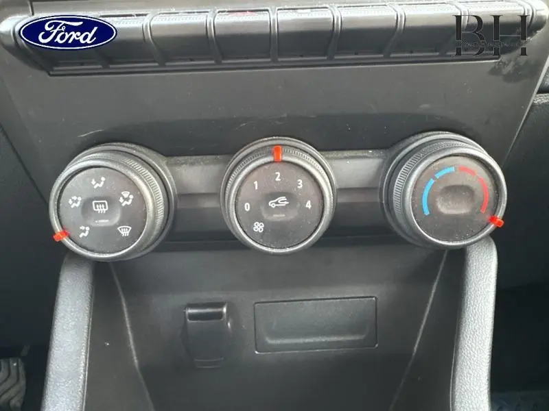 Tableau de bord noir avec commandes manuelles de climatisation de la Renault Clio blanche vue de face.