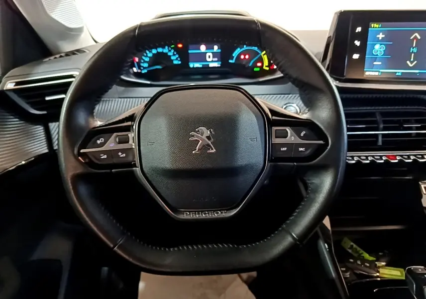 Vue intérieure centrée sur le volant cuir noir de la Peugeot 208 électrique avec tableau de bord digital et écran tactile.