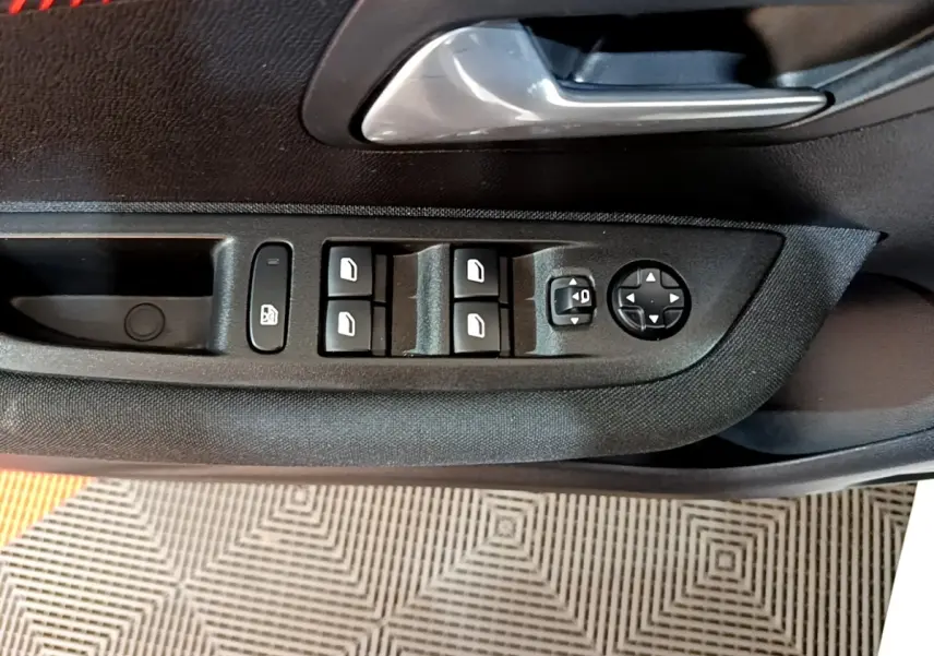 Gros plan sur la commande des vitres et réglages des rétroviseurs côté conducteur de la Peugeot 208 Electrique Active Business.