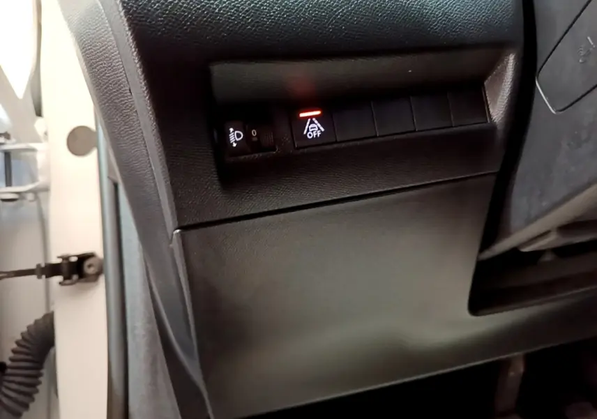 Détail du tableau de bord côté gauche d’une Peugeot 208 blanche, avec bouton d’alerte de franchissement de ligne activé.