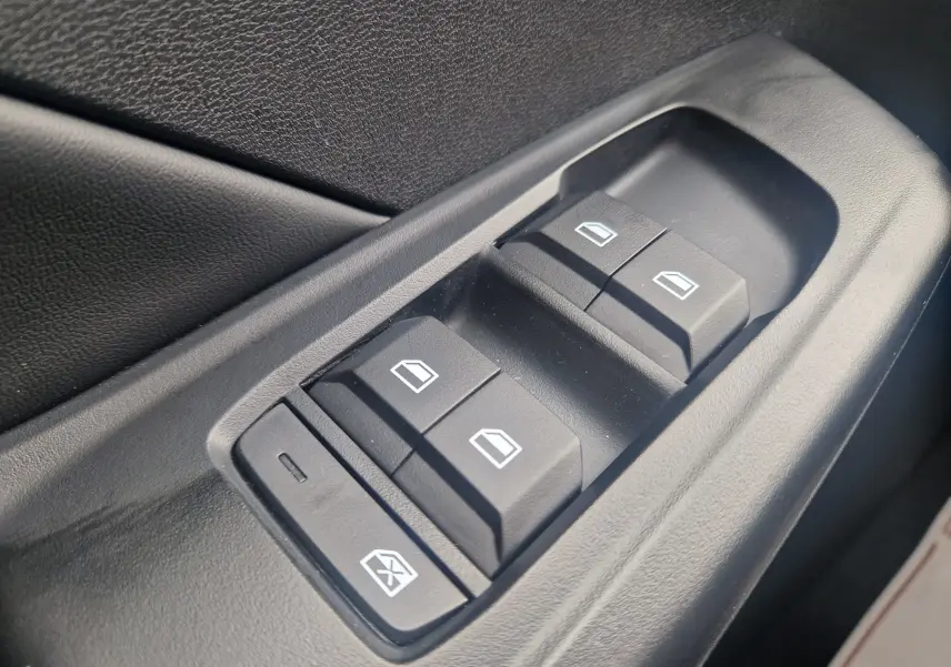 Gros plan sur les commandes de lève-vitres électriques noires côté conducteur d’un MG3 1.5L Hybrid+ 2026 en Hampstead Grey Metal.