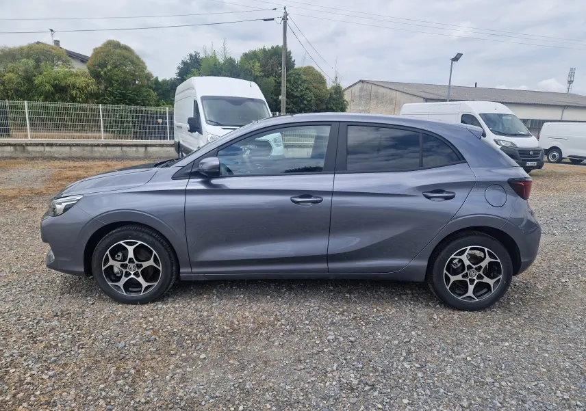 Vue de profil côté gauche d'une MG3 1.5L Hybrid+ 195CH Luxury en gris métallisé Hampstead sur un sol gravillonné.