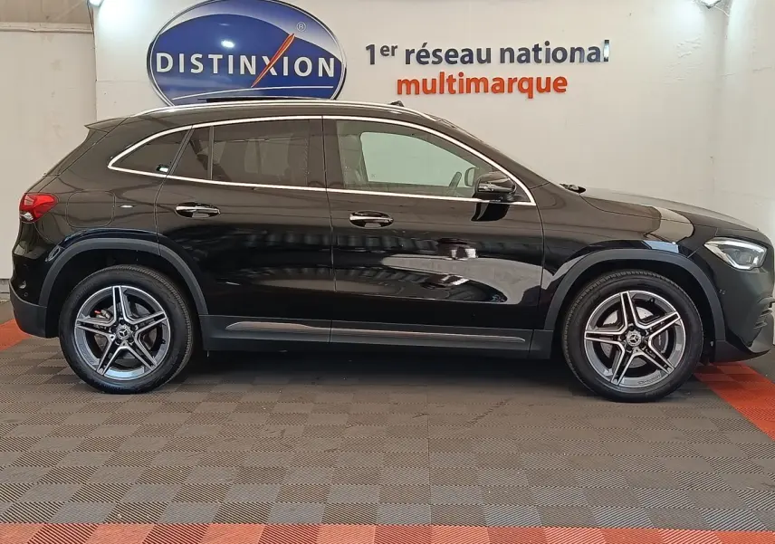 Vue latérale droite d'un Mercedes GLA 250 e AMG Line noir, avec jantes alliage et vitres teintées, en intérieur showroom.