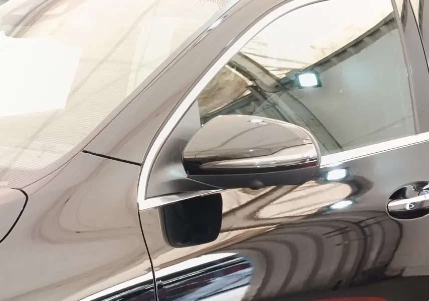 Vue rapprochée du côté gauche d’un Mercedes GLA 250 e AMG Line noir, mettant en valeur le rétroviseur et la poignée de porte.