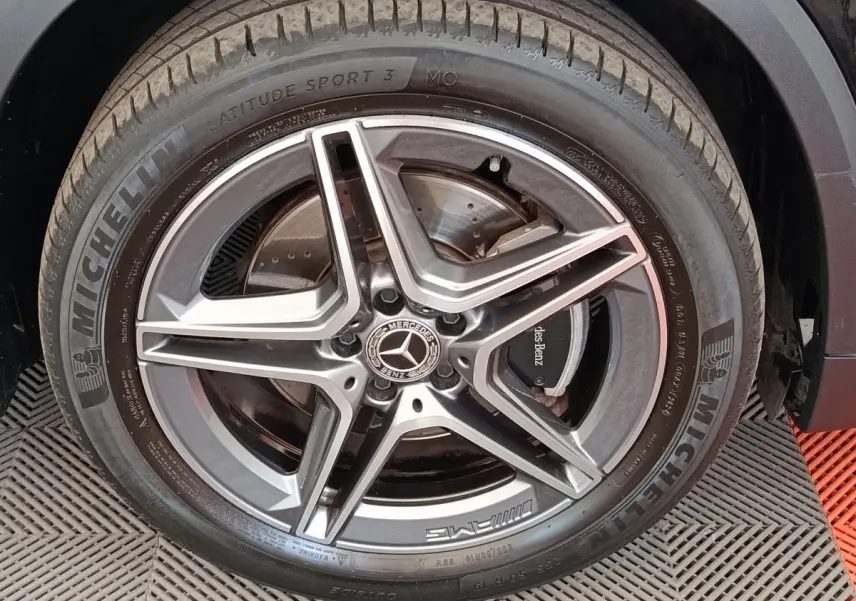 Gros plan sur la roue avant droite noire d’un Mercedes GLA 250 e AMG Line avec jante AMG étoile grise.