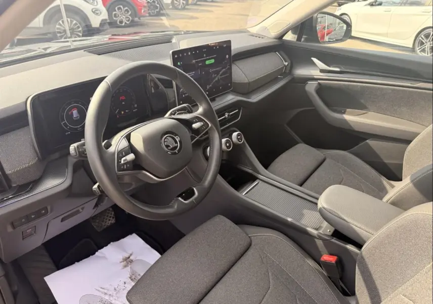 Vue intérieure côté conducteur du Skoda Kodiaq 2024 noir, montrant le volant, tableau de bord numérique et écran central tactile.