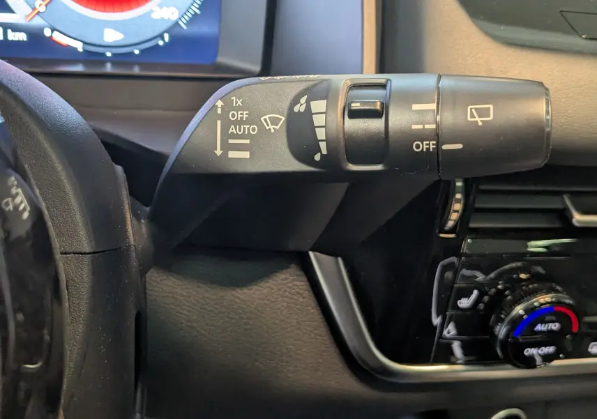 Gros plan sur la manette d’essuie-glace à gauche du volant dans l’habitacle du Nissan Qashqai blanc 2024.