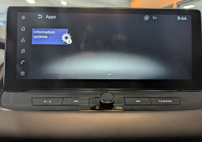 Écran tactile central du Nissan Qashqai 2024 affichant le menu "Information système" avec commandes volume et caméra en dessous.