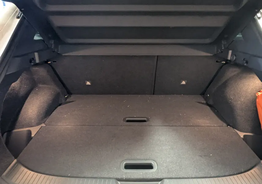 Vue intérieure du coffre du Nissan Qashqai blanc 2024, montrant l'espace de rangement avec banquette arrière rabattue.