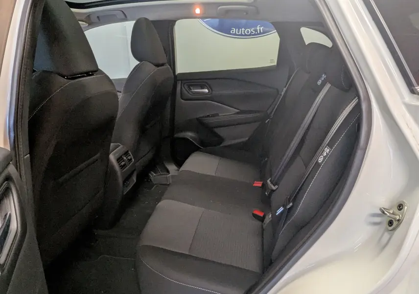 Vue intérieure côté droit sur la banquette arrière noire du Nissan Qashqai blanc 2024 avec porte ouverte.