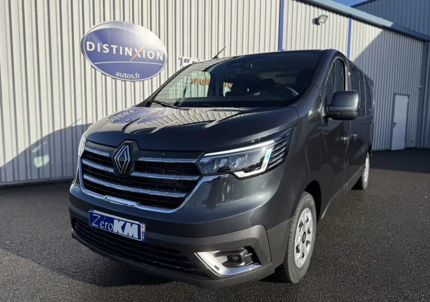 Renault Trafic Combi gris comète en 3/4 avant droit, fourgon 9 places avec calandre chromée et phares LED.