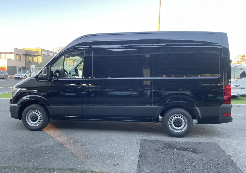 Profil latéral gauche d'un Volkswagen Crafter Van noir intense 2025, version longue et haute, sans fenêtres latérales arrière.