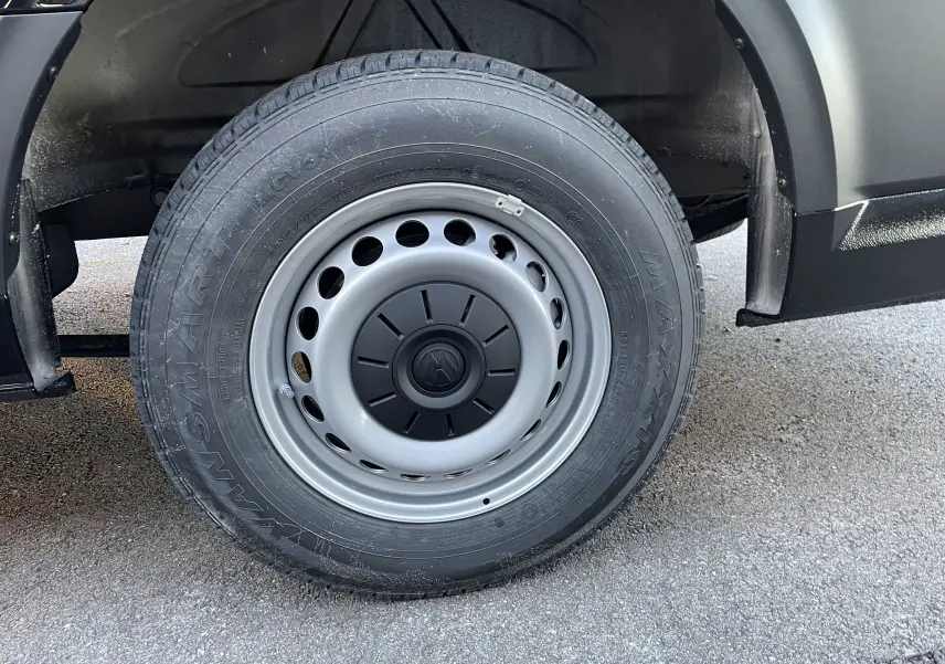 Gros plan sur la roue avant droite du Volkswagen Crafter Van noir intense, jante acier grise avec logo VW central.
