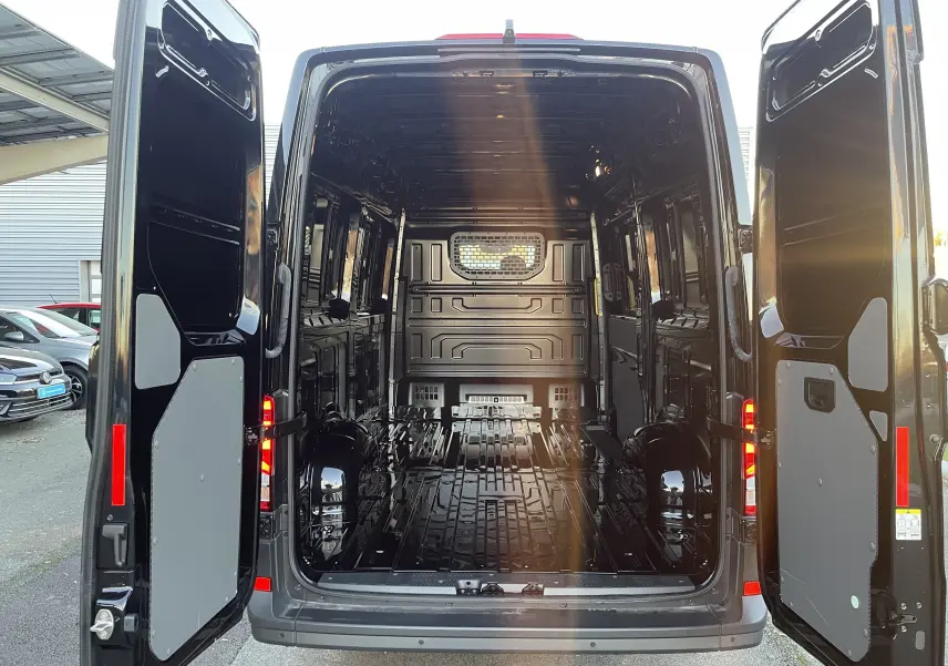 Vue arrière du Volkswagen Crafter Van noir intense 2025 avec portes ouvertes montrant l’espace de chargement vide et la cloison vitrée.