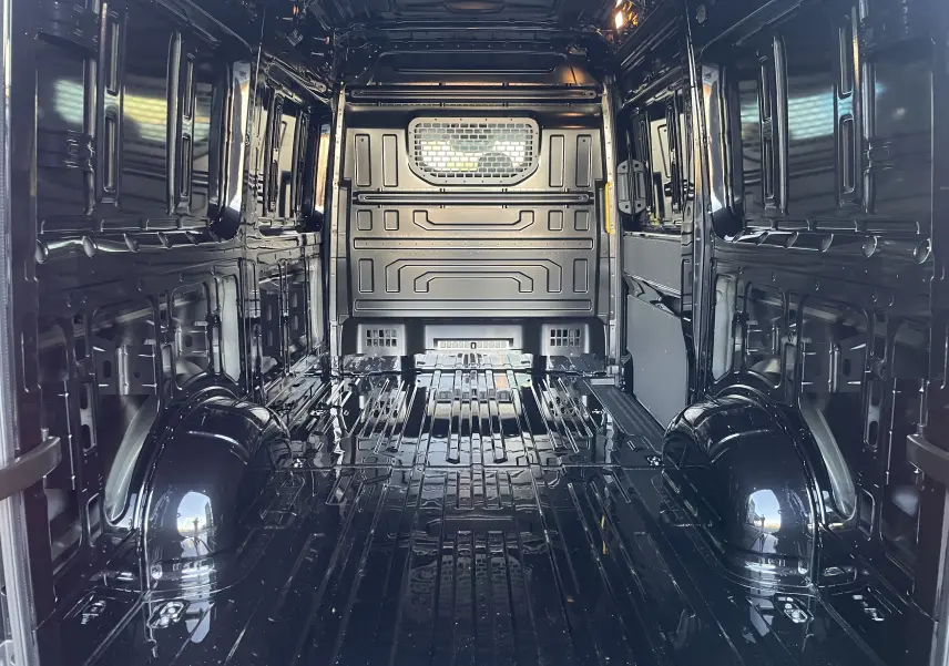 Vue intérieure arrière du Volkswagen Crafter Van noir intense, montrant l'espace de chargement vide et la cloison avec vitre fixe.