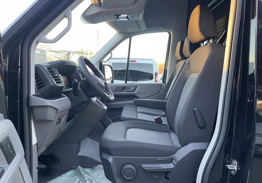 Vue latérale intérieure côté conducteur du Volkswagen Crafter Van noir intense 2025, montrant les sièges avant et le tableau de bord.