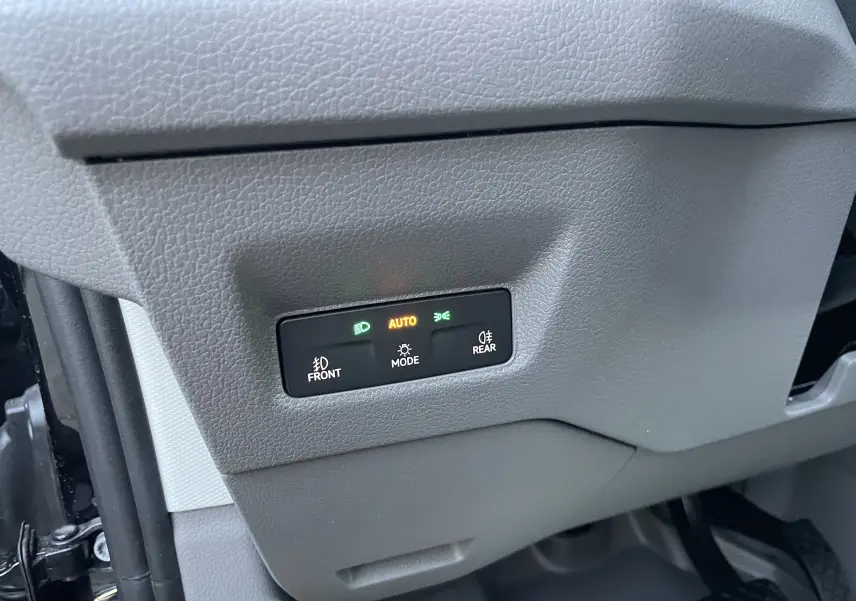 Bouton de commande des phares avec éclairage automatique dans l'habitacle gris du Volkswagen Crafter Van noir intense 2025.