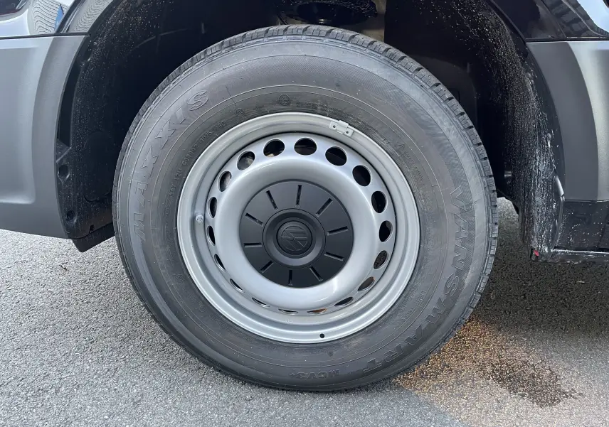 Gros plan sur la roue avant droite du Volkswagen Crafter Van noir intense, jante acier avec logo VW central.