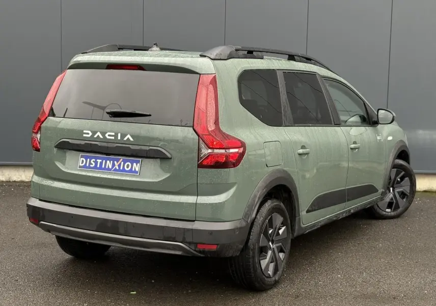 Vue 3/4 arrière droite d'un Dacia Jogger 2025 kaki lichen avec barres de toit et jantes spécifiques.