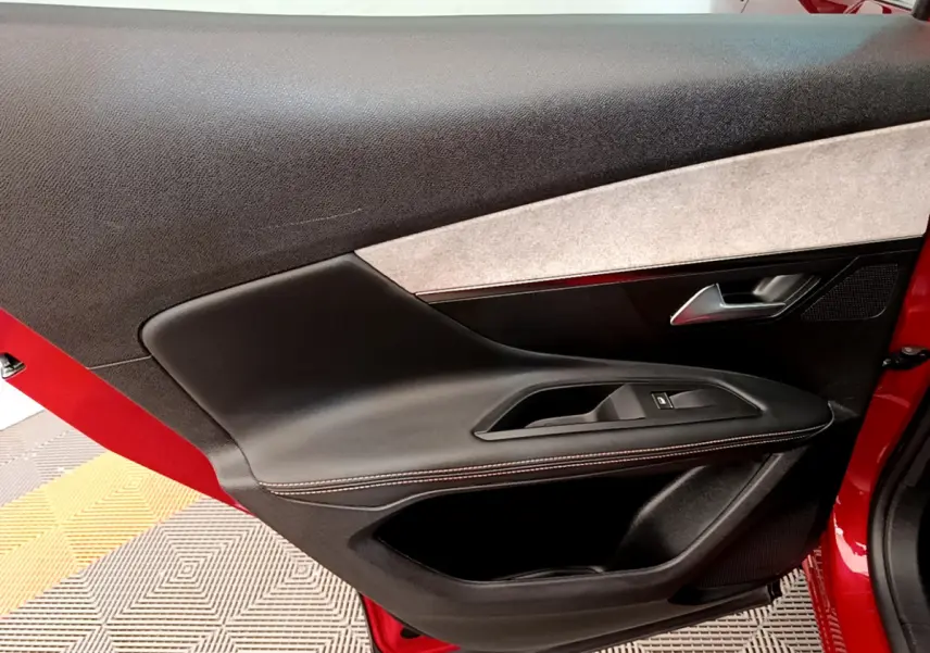 Vue rapprochée de la porte avant gauche rouge du Peugeot 3008 GT 2021, avec garniture noire et poignée argentée.