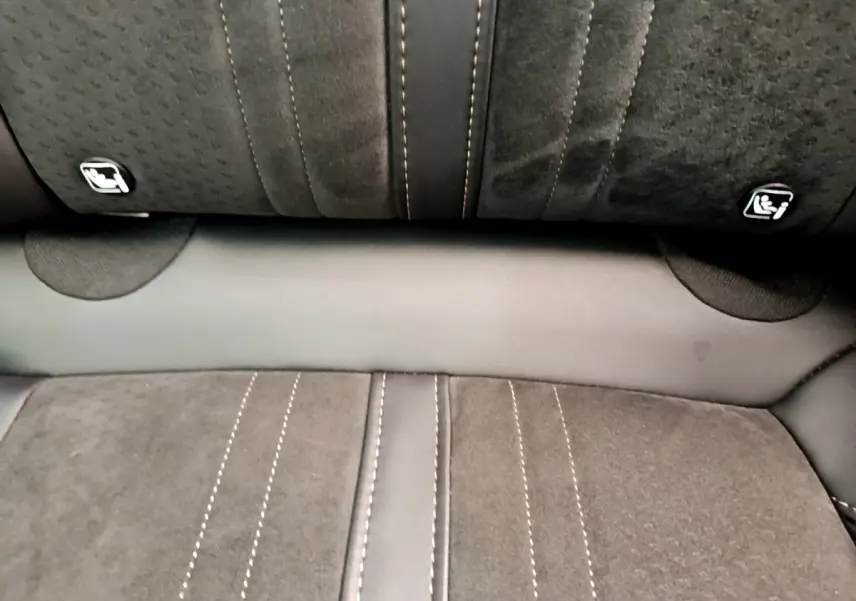 Gros plan sur la banquette arrière en tissu noir avec surpiqûres blanches et fixations Isofix visibles.