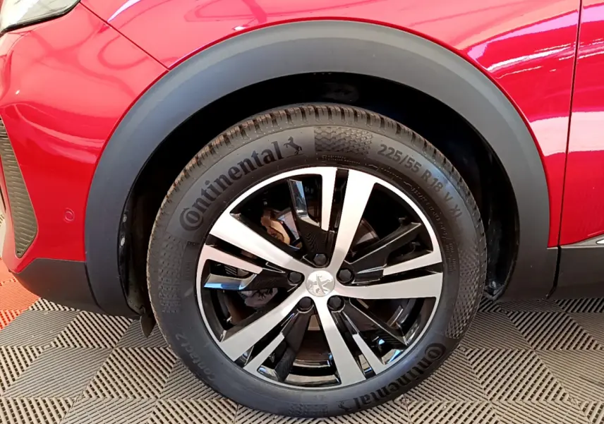 Gros plan sur la roue avant gauche d’un Peugeot 3008 GT rouge avec jante alliage bicolore et pneu Continental.