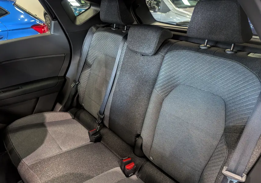 Vue intérieure sur les sièges arrière en tissu gris du Renault Captur E-TECH Full Hybrid 2026, avec ceinture de sécurité visible.