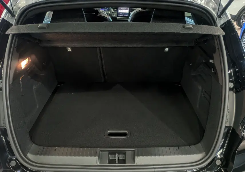 Coffre ouvert vu de l'arrière d'un Renault Captur noir avec toit gris, montrant un espace de chargement vide et propre.