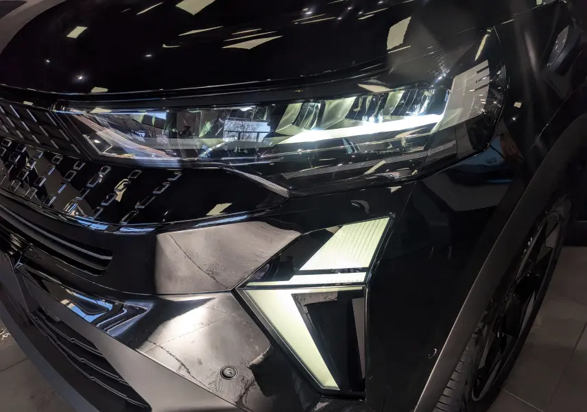 Gros plan sur l'avant droit noir brillant du Renault Captur E-Tech 2026, mettant en valeur ses phares LED et sa calandre distinctive.