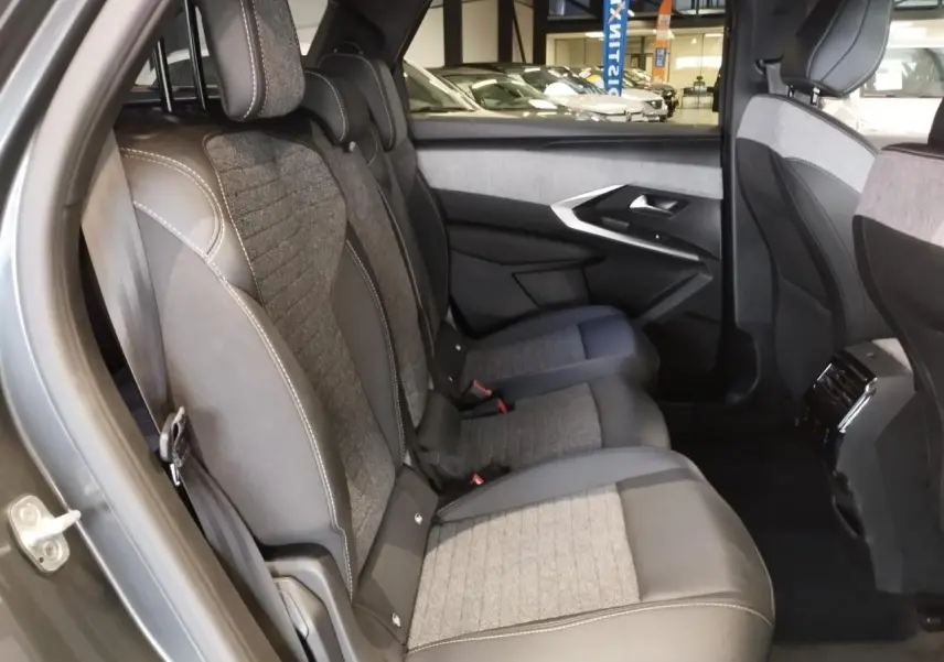 Vue côté gauche des sièges arrière gris tissu et cuir du Peugeot 5008 2025 avec détails couture blanche et habillage de porte assorti.