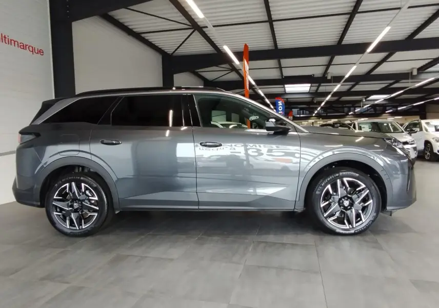 Peugeot 5008 gris titanium vue de profil côté droit en intérieur avec jantes alliage 19 pouces diamantées.