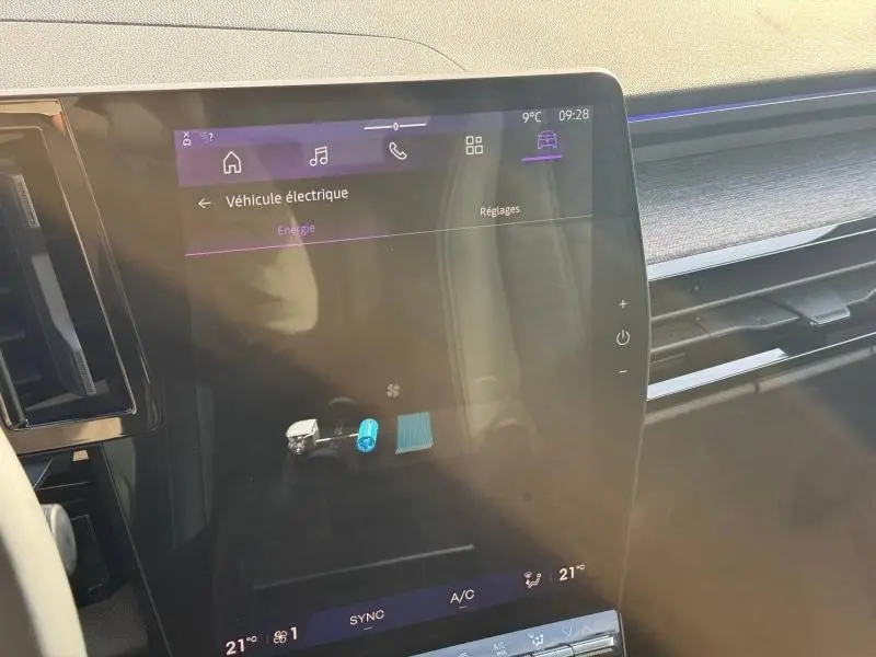 Écran tactile intérieur du Renault Austral 2025 affichant les réglages du véhicule électrique, avec tableau de bord en bois clair.