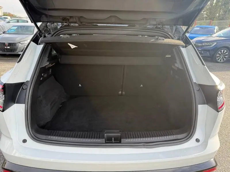 Coffre ouvert vu de l'arrière du Renault Austral blanc nacré avec toit noir étoilé, montrant l'espace de chargement vide.