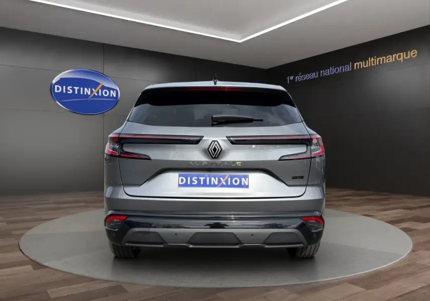 Vue arrière d'un Renault Austral gris foncé avec feux LED horizontaux et logo central lumineux dans un showroom.