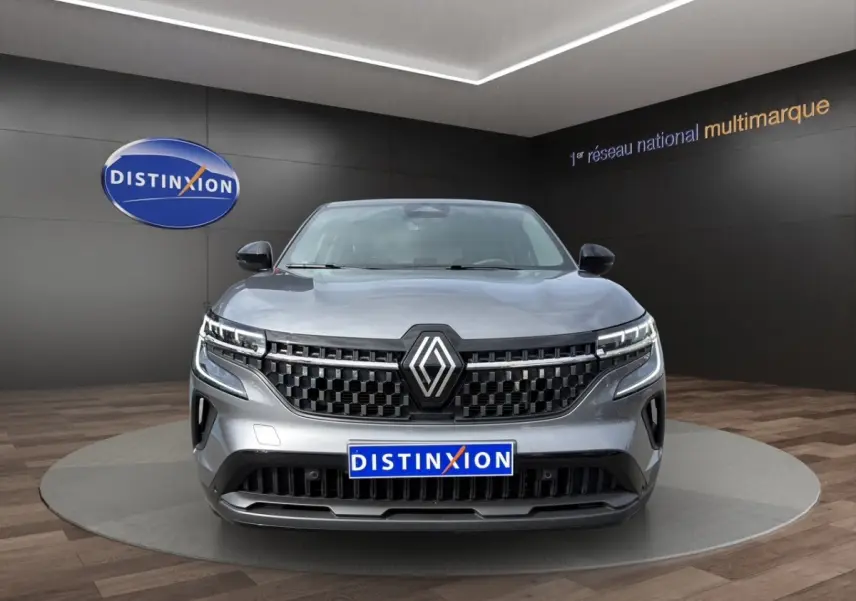 Vue frontale d’un Renault Austral gris foncé avec calandre noire et feux LED distinctifs en showroom.