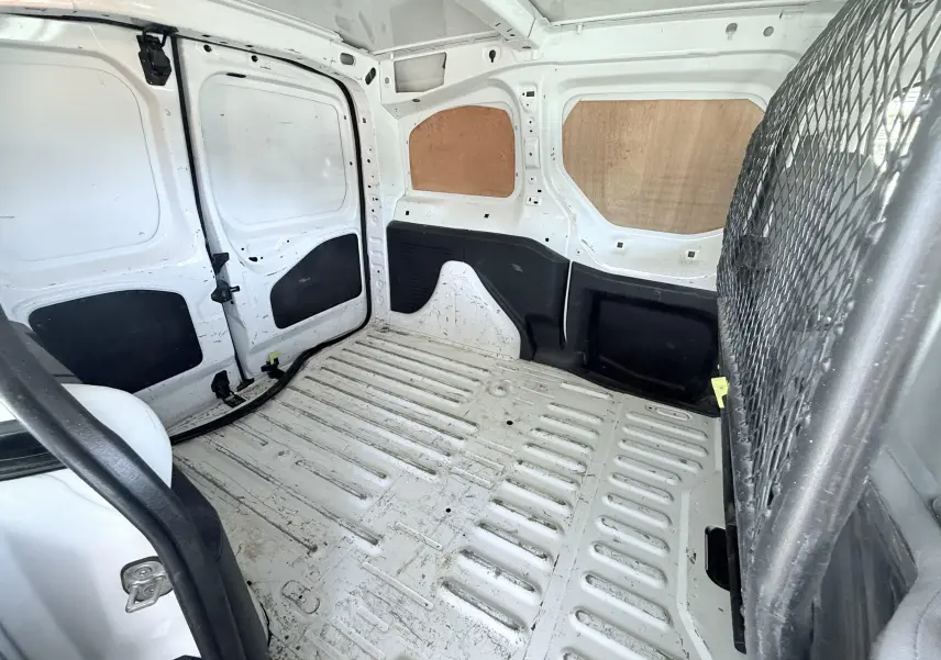 Intérieur du coffre blanc du Peugeot Partner 2014, vue en plongée montrant la cloison métallique et le plancher strié.